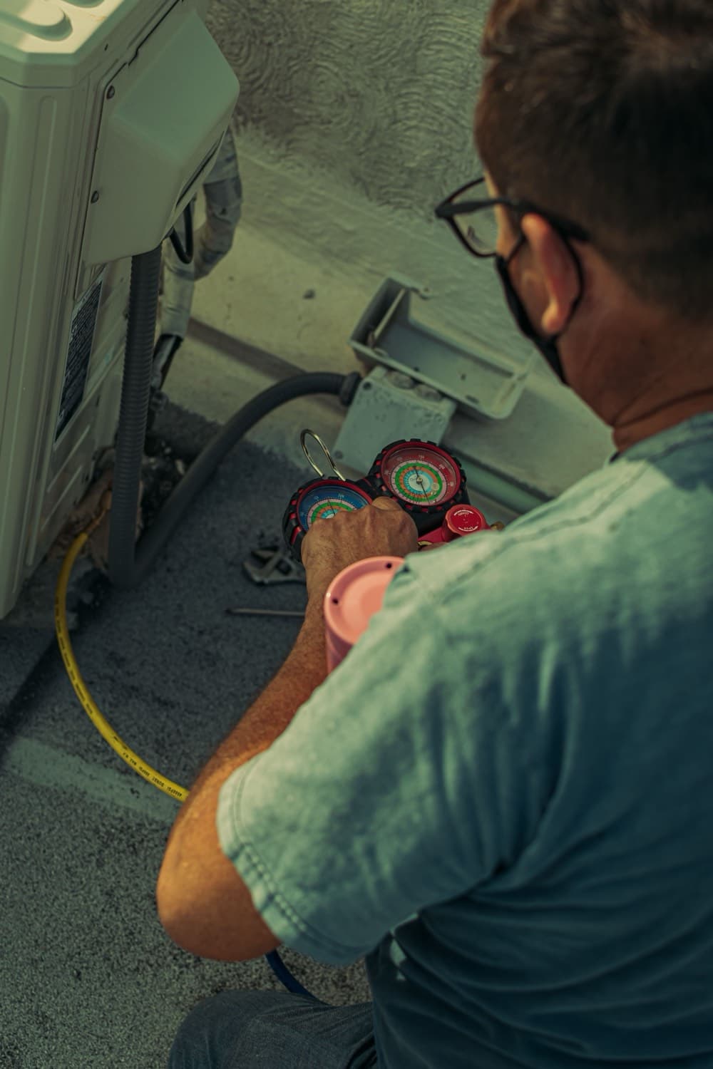 A technician servicing an HVAC unit with refrigerant gauges