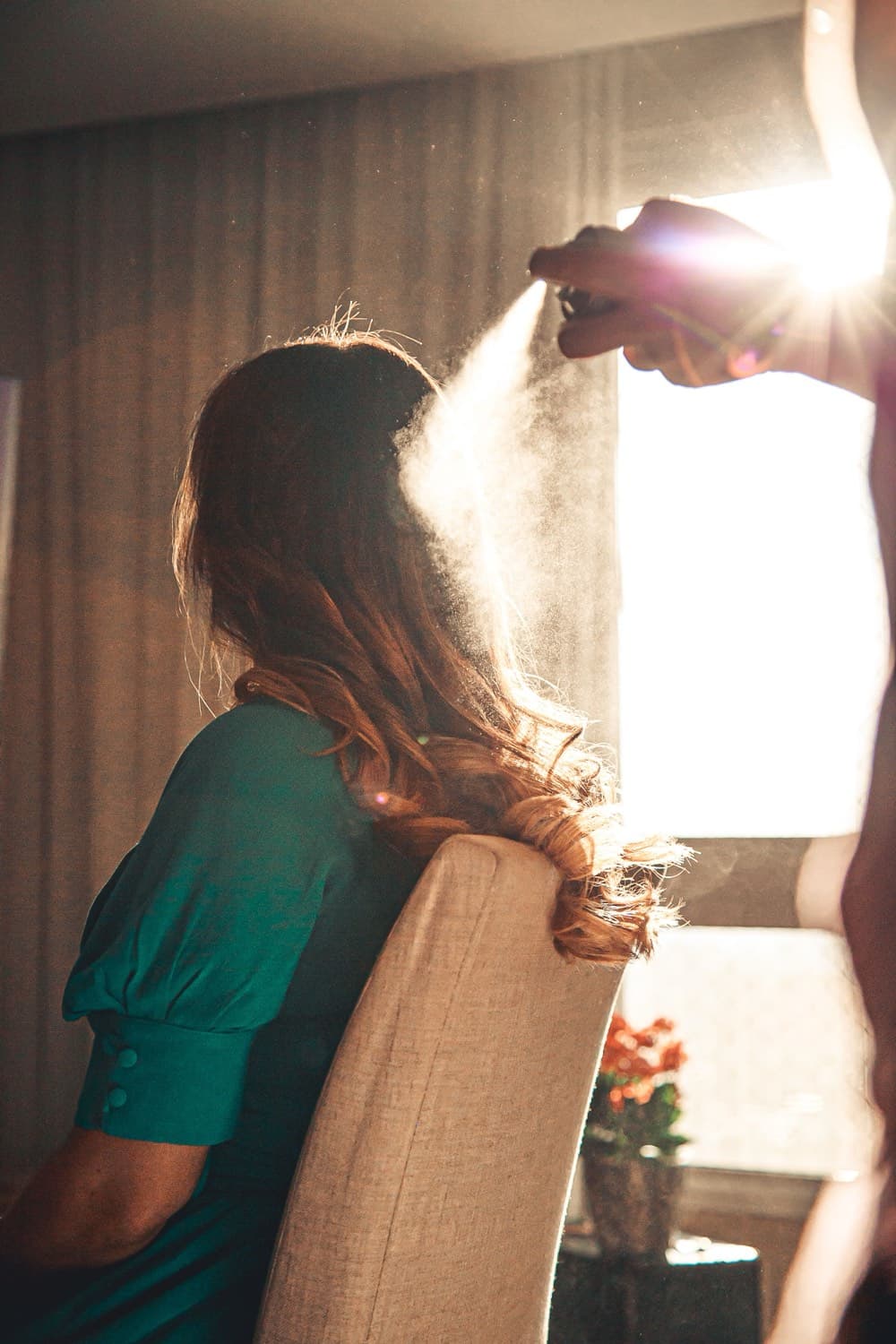 A stylist finishing a client's hair in warm light